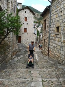 Un homme pousse une poussette dans les rues de Sainte-Enimie en Lozère